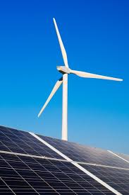 Solar panels and wind turbines against a clear blue sky, showcasing renewable energy sources in a sustainable landscape.