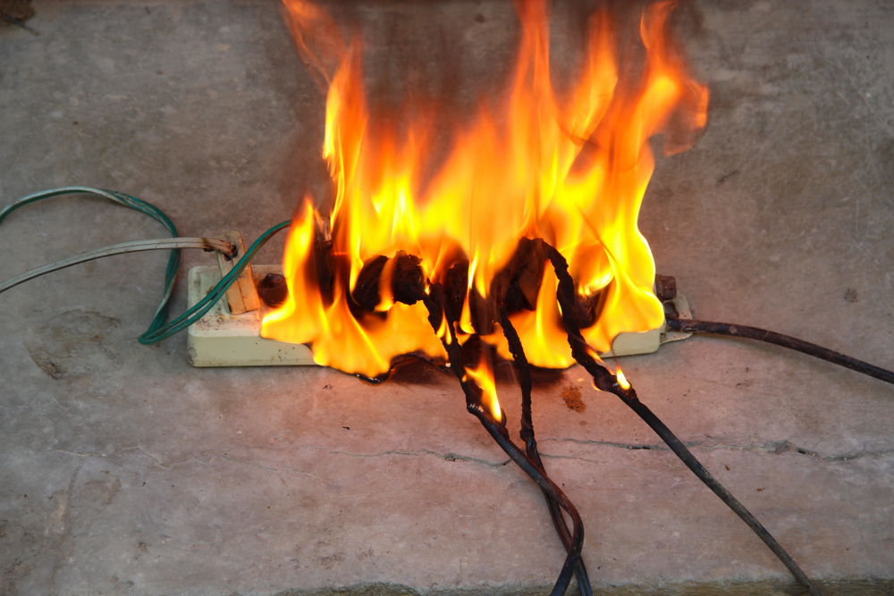 A fire burns inside a box surrounded by tangled wires, creating a hazardous situation.